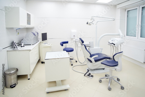 New interior of a dental office with white and blue furniture, dental chair, wet milling and grinding machine, intra oral scanner. Dentist’s office. Dental laboratory
