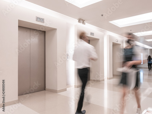 People are walking in office past elevators, Modern steel elevator cabins in a business lobby or Hotel, Store, interior, office,perspective wide angle