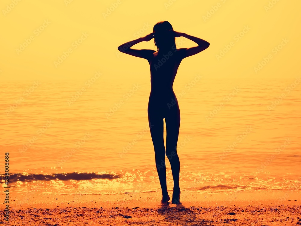 Silhouette of a skinny young girl walking along the beach