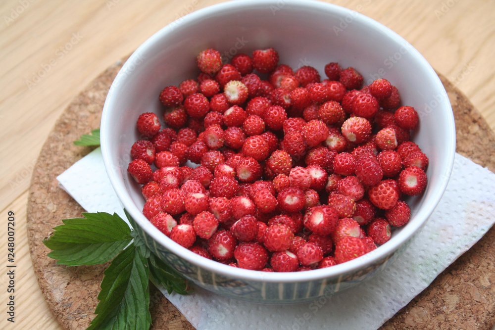 Fresh wild strawberries in a bowl on wooden table Fresh wild strawberries in a bowl on wooden table