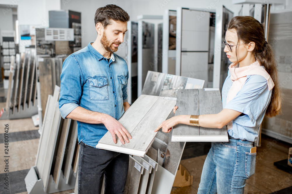Obraz premium Beautiful young couple choosing ceramic tiles for their house repairment in the building shop