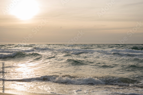 Scenic view of the waves of the blue sea on the sandy shore. Wild nature. Storm. Sunset on the sea.