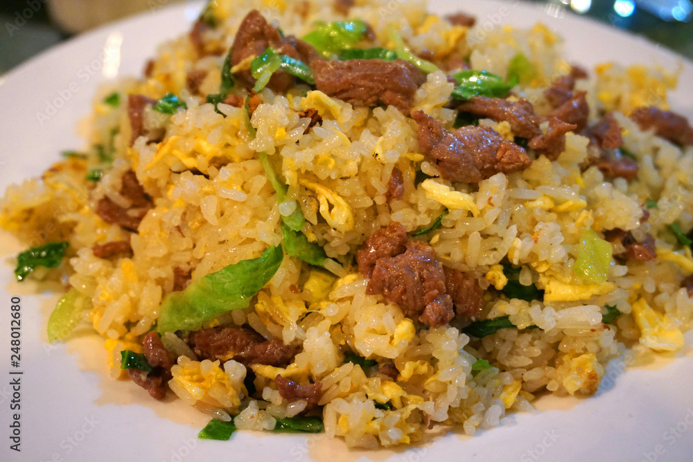 Stir fried rice with beans carrot shrimp pork egg sausage onion beef chillies on white plate Vietnamese traditional food Asian cuisine Stir fried rice with beans carrot shrimp pork egg sausage onion beef chillies on white plate Vietnamese traditional food Asian cuisine