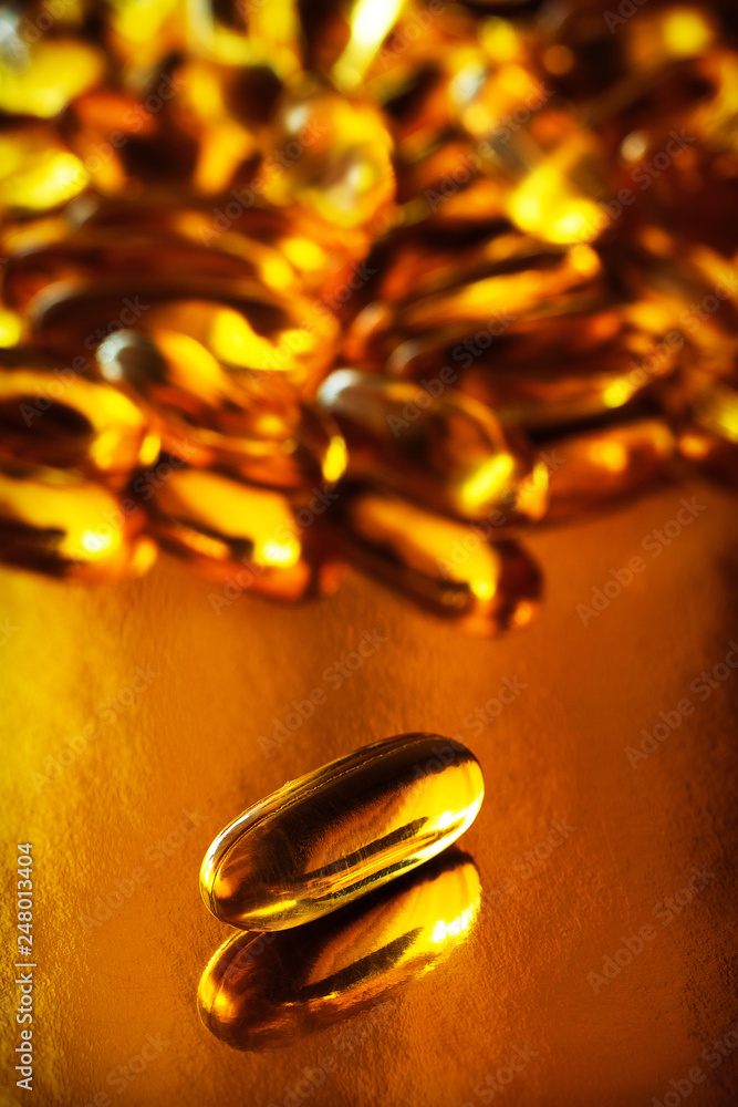 Fish oil capsules on a gold background. Omega-3, vitamin D, supplements. Healthy lifestyle. Close-up, macro. Fish oil capsules on a gold background. Omega-3, vitamin D, supplements. Healthy lifestyle. Close-up, macro.