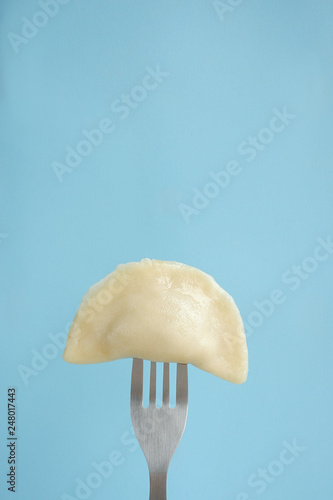 Dumpling on a blue background. Food on fork