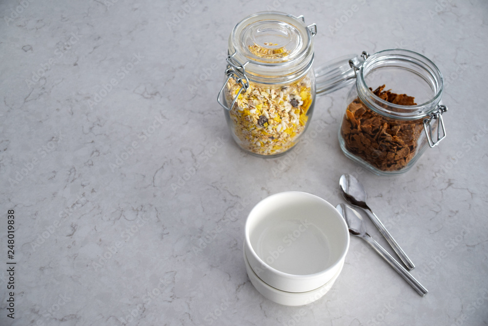 White bowls, spoons and jars filled with cereals