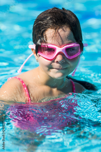 girl in pink glasses in the pool with her head above the water
