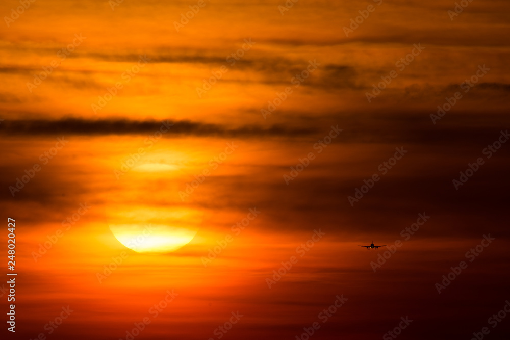 Airplane  silhouette  in the sunset with red sky and big sun 