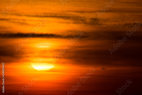 Airplane  silhouette  in the sunset with red sky and big sun 
