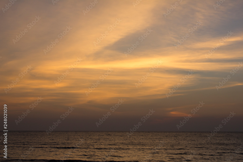 yellow and white clouds in the blue purple sunset sky against the sea