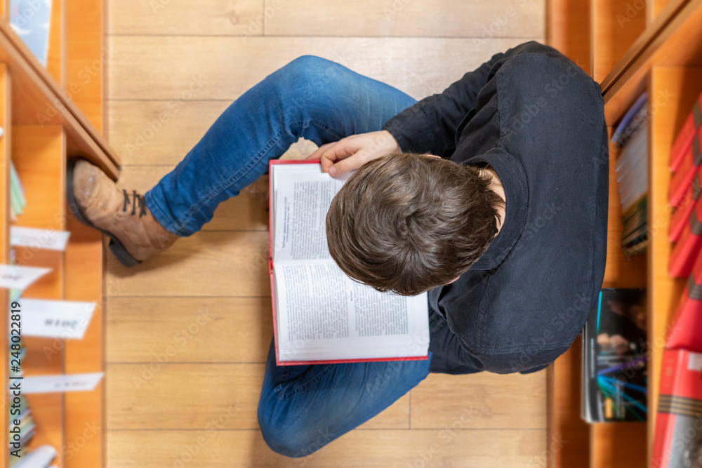 top view of student lay on wooden floor and read a book b top view of student lay on wooden floor and read a book b