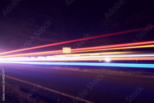 Colorful light beams of moving vehicles on busy highway at dusk