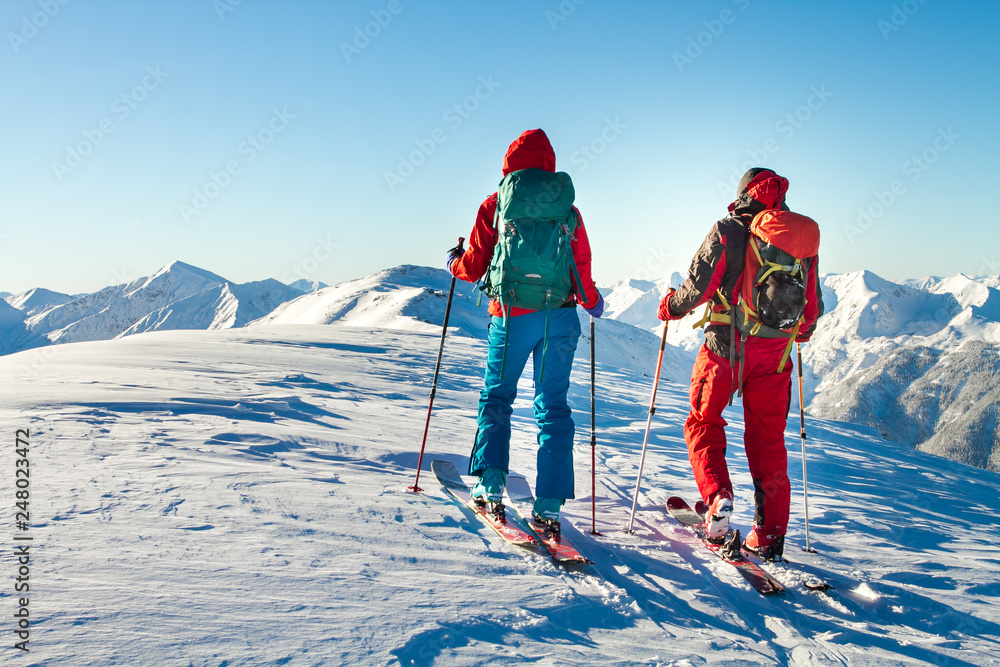 Man and woman ski tourer enjoying the view on a summit in the alps.