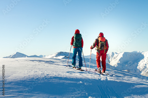 Man and woman ski tourer enjoying the view on a summit in the alps.