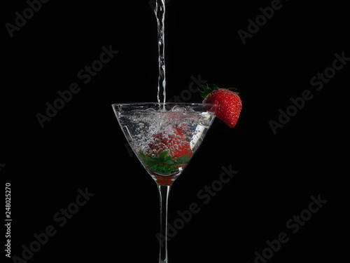 cocktail with splash and strawberry isolated on black background