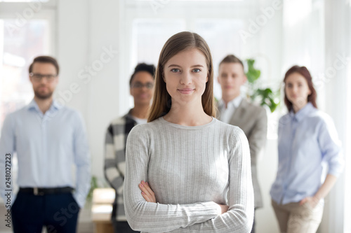 Female leader smiling looking at camera with team at background photo