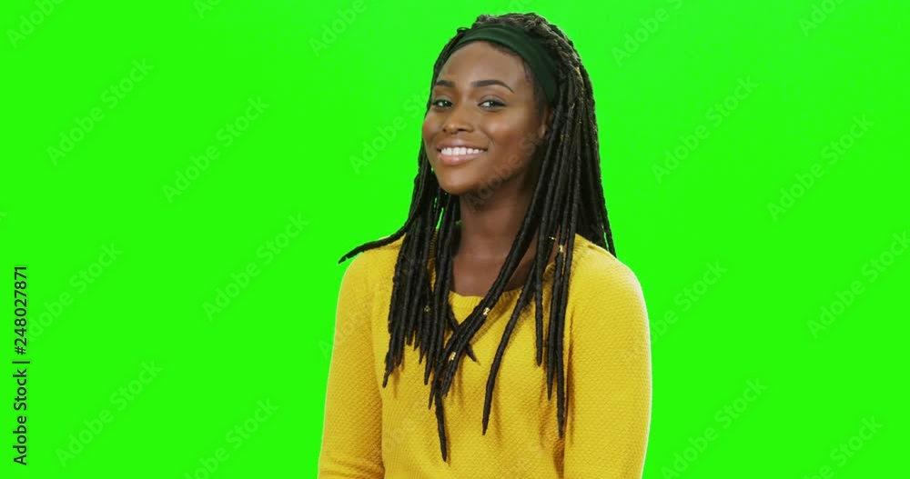Young African American beautiful girl with long hair in braids smiling and posing to the camera on the green screen background. Portrait. Young African American beautiful girl with long hair in braids smiling and posing to the camera on the green screen background. Portrait.