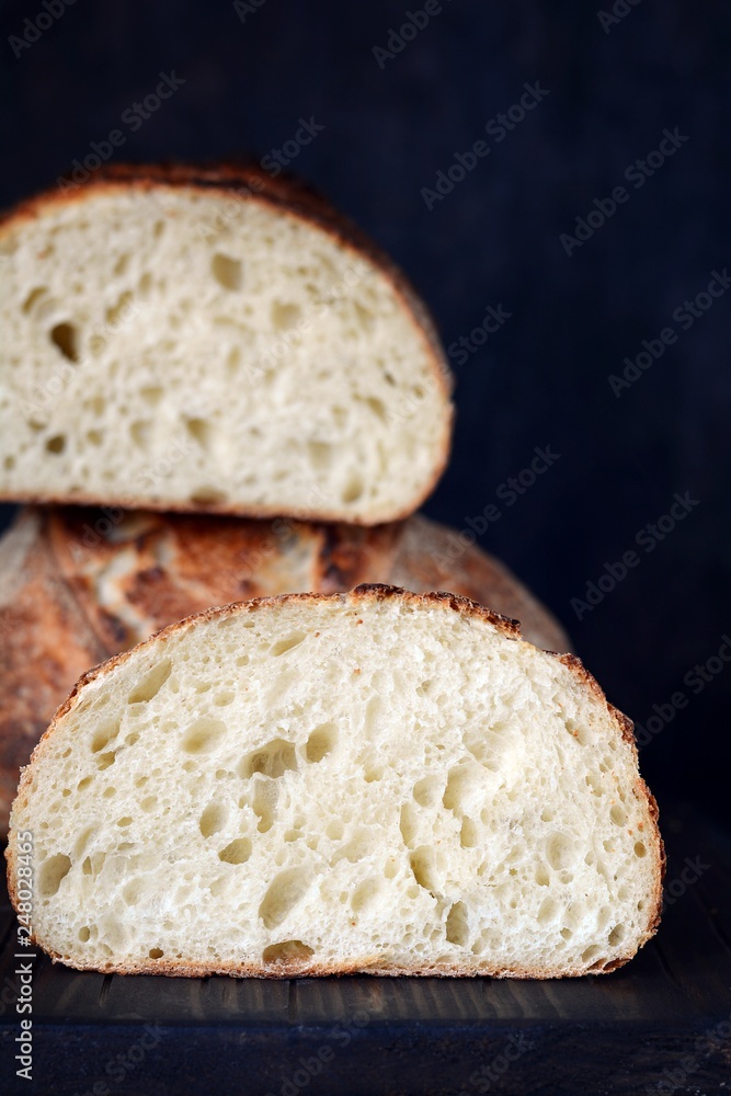 Fresh homemade bread on a dark background, on whole wheat flour. French bread round shape. Bread baking. Unleavened bread