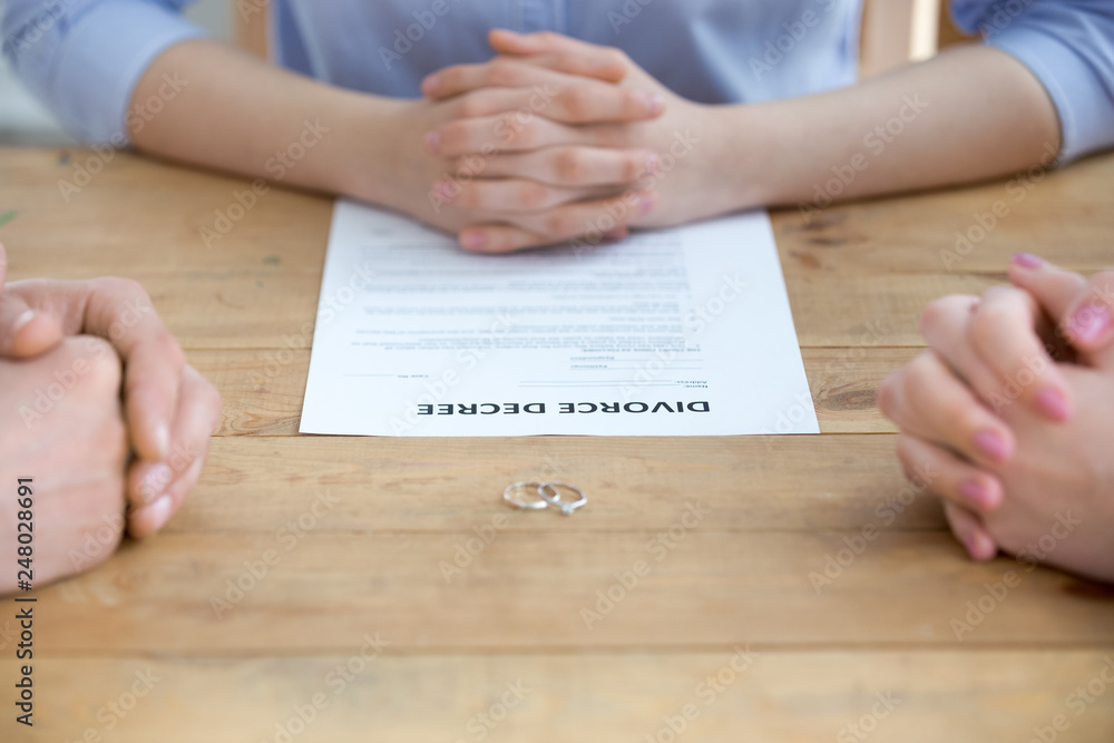 Couple getting divorced in lawyers office with decree paper, closeup Couple getting divorced in lawyers office with decree paper, closeup