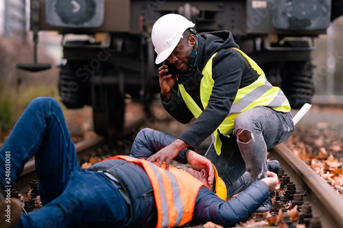 Railroad engineer injured in an accident at work. Railroad engineer injured in an accident at work on the railway tracks. Coworker calling for help photo