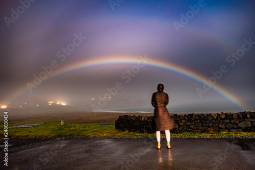 Lady observing very rare moonbow during the night above Staffin bay - Isle of Skye, Scotland photo