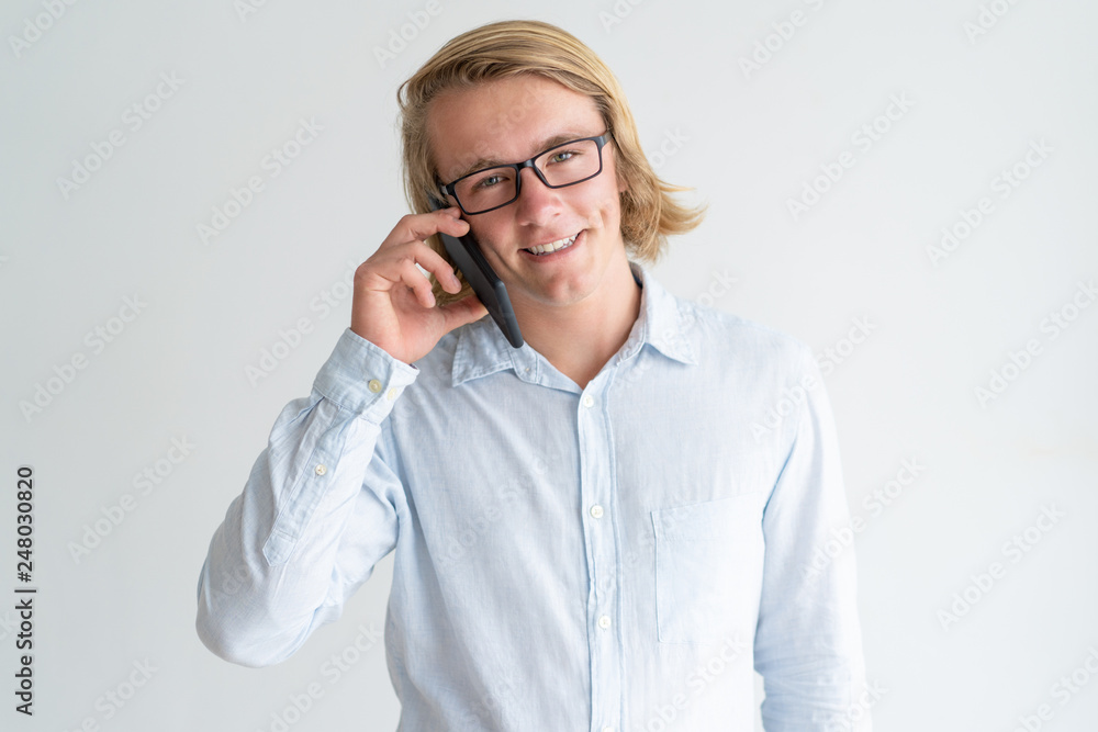 Smiling young man talking on smartphone and looking at camera Smiling young man talking on smartphone and looking at camera