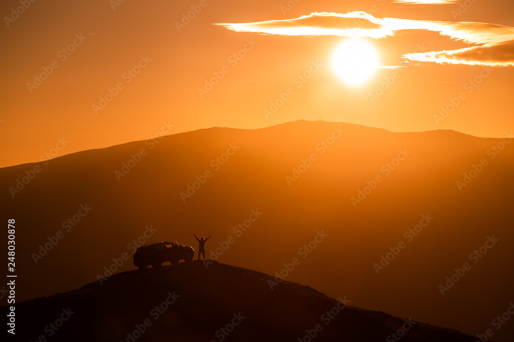 Silhouette of  travel adventurer with off road car on top of the mountain  