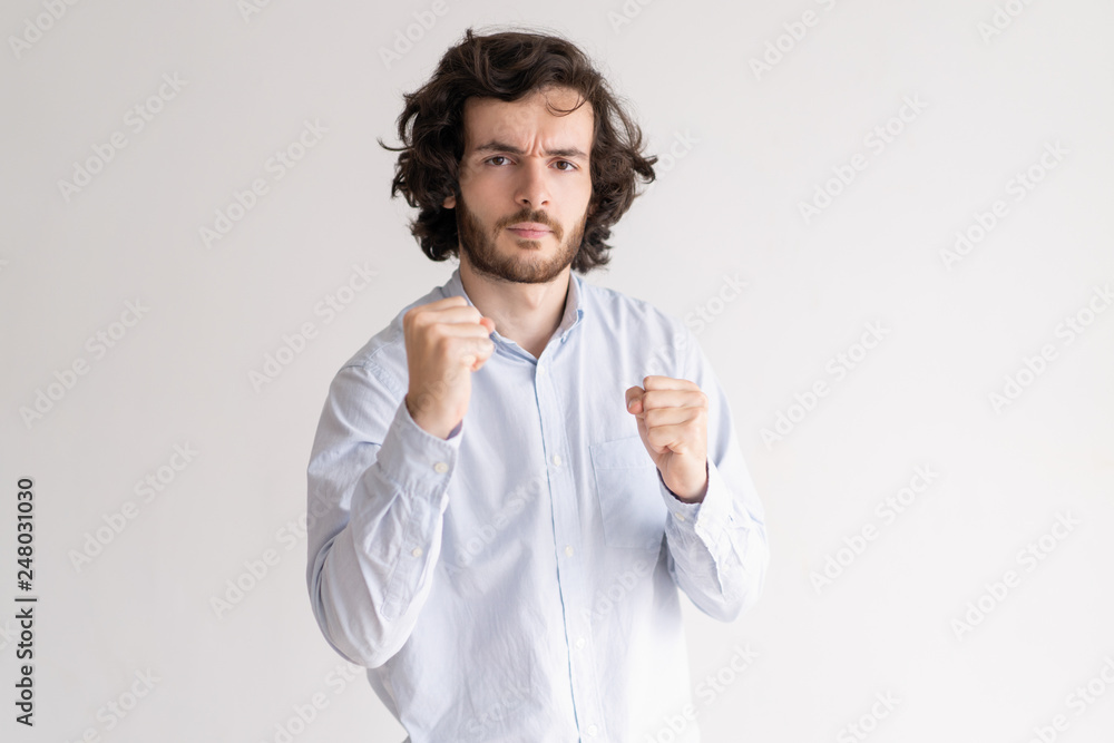 Tensed young man standing in boxing pose and looking at camera Tensed young man standing in boxing pose and looking at camera