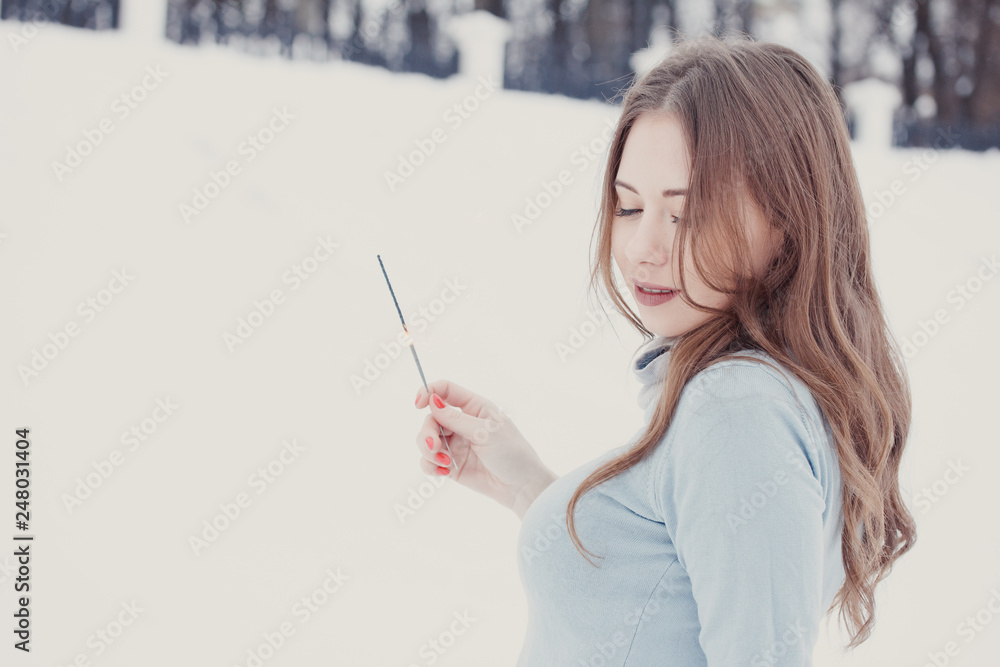 Happy and smiling girl keeps Bengal lights on the street during snowfall. Winter concept Happy and smiling girl keeps Bengal lights on the street during snowfall. Winter concept
