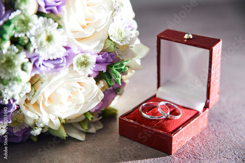 Rings in a box and A Bridal bouquet with white roses and green on a dark background