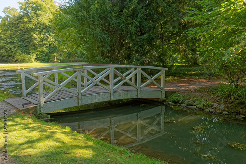 Small wooden bridge over a stream with trees in the background.