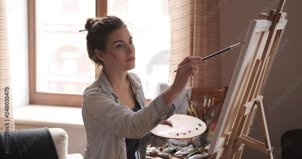 Young female artist painting picture using watercolor paint on canvas Young female artist painting picture using watercolor paint on canvas