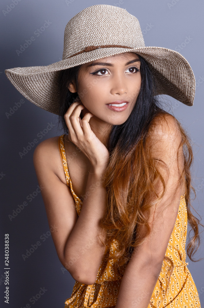 A portrait of an attractive woman sitting and wearing a summer hat A portrait of an attractive woman sitting and wearing a summer hat