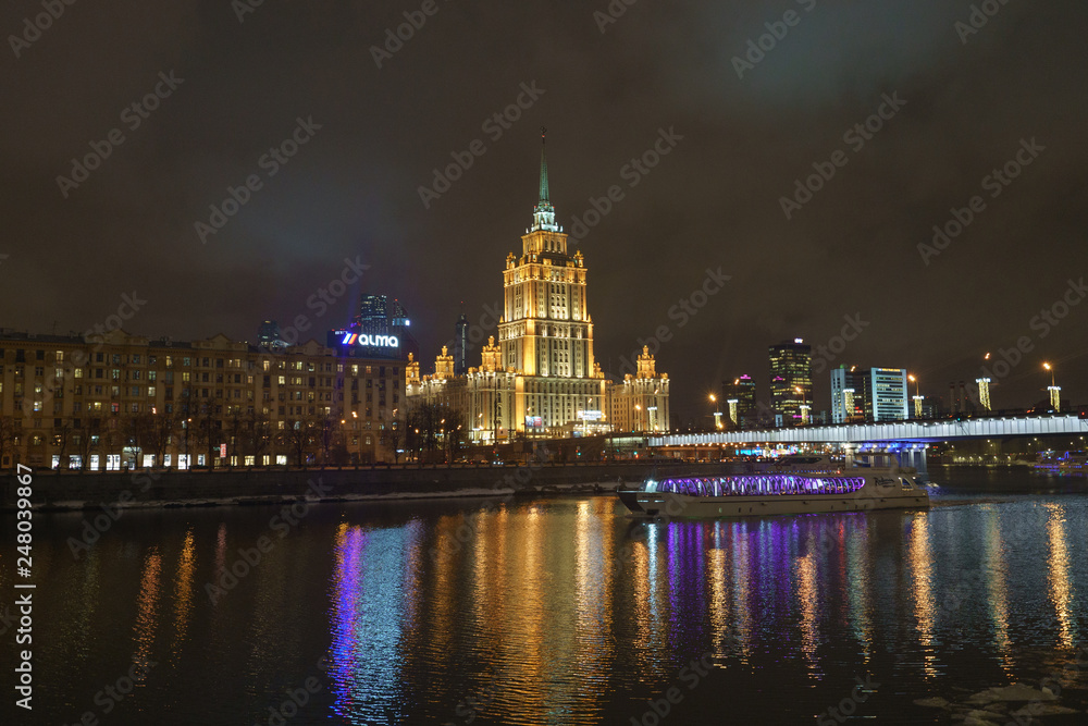 Hotel Ukraine (Radisson Royal Hotel) in bright lights and Moskva river in night winter reflections of the night Moscow.