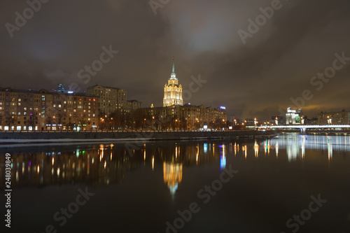 Hotel Ukraine (Radisson Royal Hotel) in bright lights and Moskva river in night winter reflections of the night Moscow.