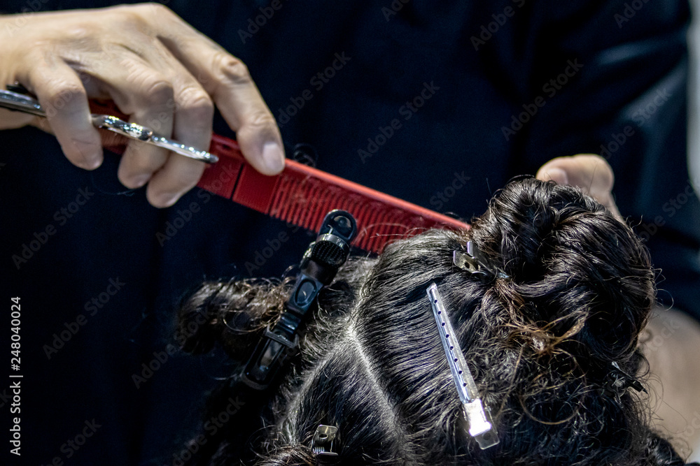 Naklejka premium Primer plano de peluquero peinando y cortando el pelo a una mujer