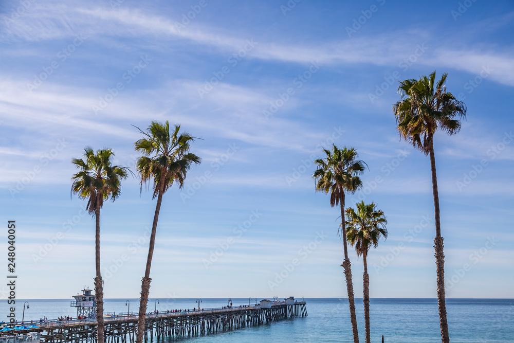 The pier and palm trees at San Clemente beach, with a blue sky overhead