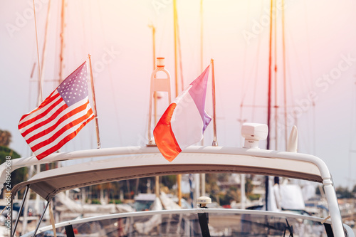Closeup flags of France and United States on white yacht with light of sun