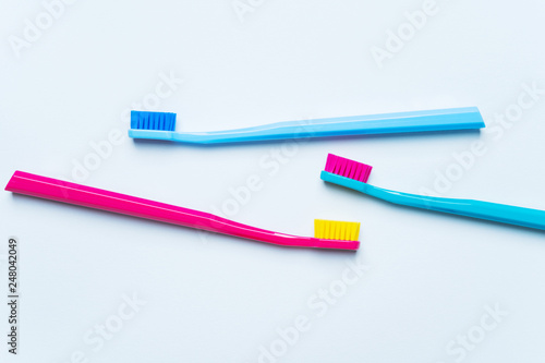 Colorful tooth brushes with bright color bristles on a light pastel blue background. Dental tools with empty space for text for  your mockup.