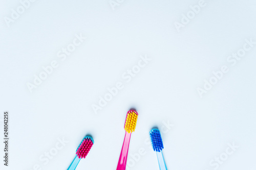 Colorful tooth brushes with bright color bristles on a light pastel blue background. Dental tools with empty space for text for  your Stomatologist mockup.