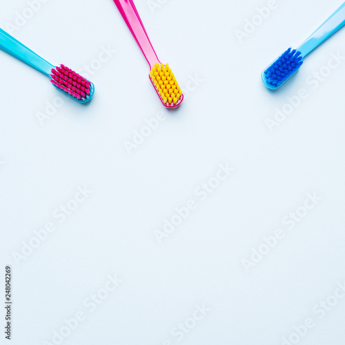 Colorful tooth brushes with bright color bristles on a light pastel blue background. Dental tools with empty space for text for  your mockup.