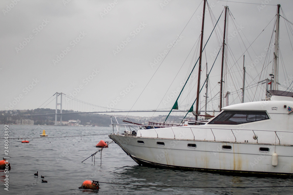 Fototapeta premium Yacht waiting moored at the port and the bridge in the background.
