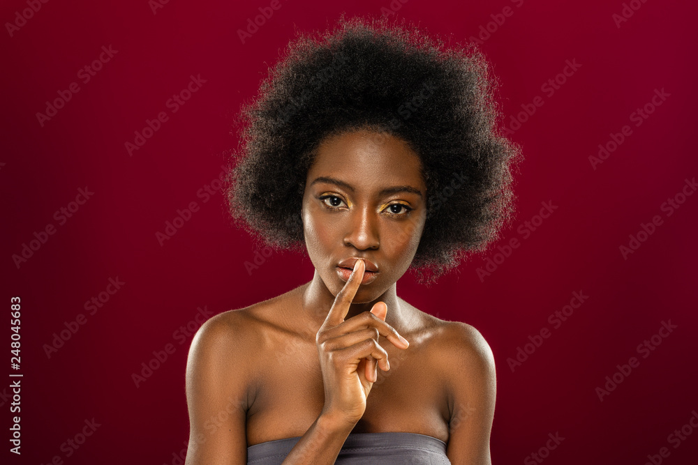 Pleasant young woman putting her finger to the lips Pleasant young woman putting her finger to the lips