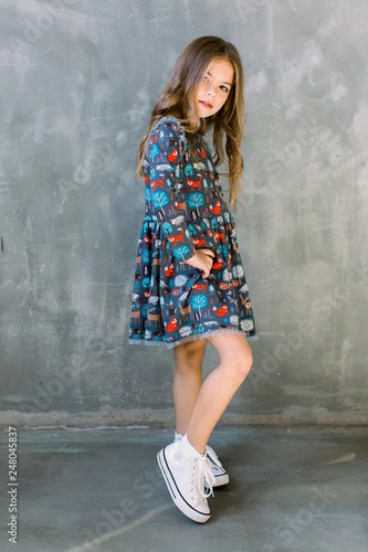 Fashion little girl child in blue dress on a grey background © sofiko14