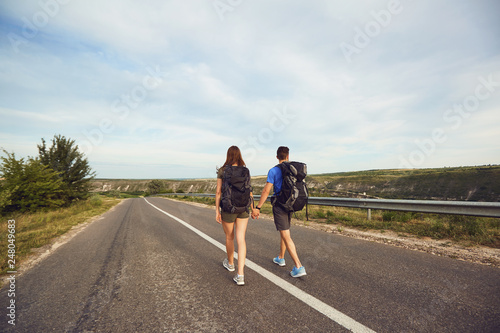 Travelers with backpacks go on the road in nature