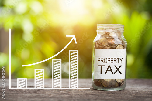 Property Tax Word With Coin In Glass Jar and graph up. Financial Concept