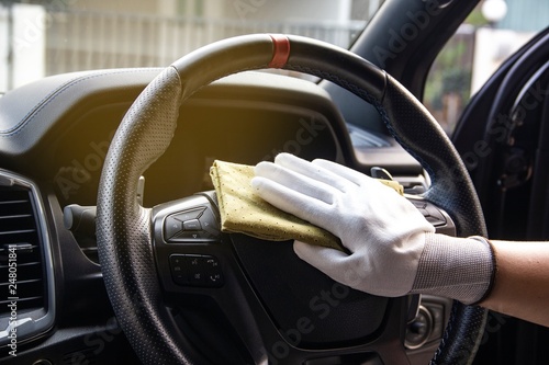 This image is a picture of wiping the car by a yellow microfiber cloth with hand wearing gloves.Car wash concept.