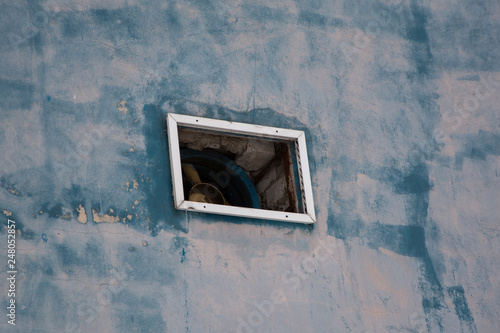 Blue concrete wall background, texture. Window and fan in the wall. photo