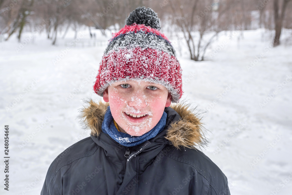 Fototapeta premium A boy’s portrait in winter time. A close-up. The whole face in the snow.