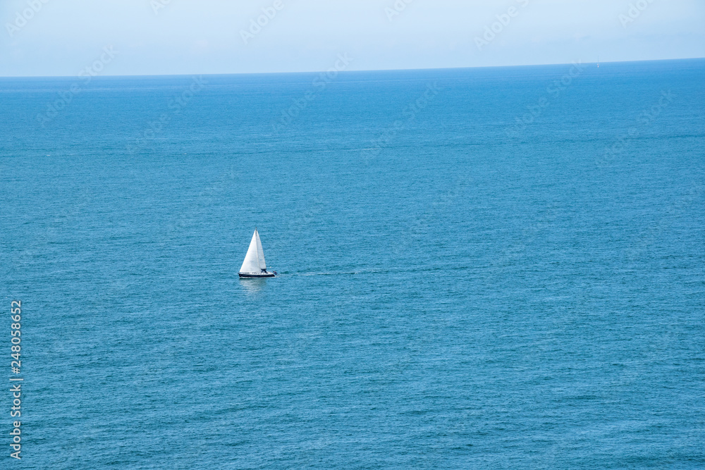 Sailboat floats alone on open sea in France at the north coast